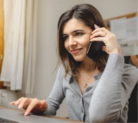 a woman smiling while working on her laptop img-border