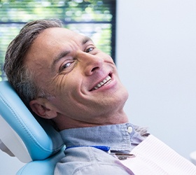 Man smiling while sitting in dental chair wearing collared shirt.