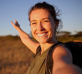 Woman outside with arm outstretched smiling in the sunshine