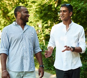 Two men walking and talking together outside