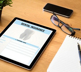 Dental insurance form on tablet next to notepad