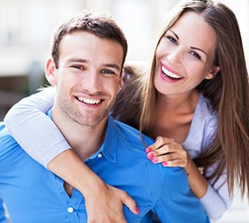 A young couple smiling and hugging.