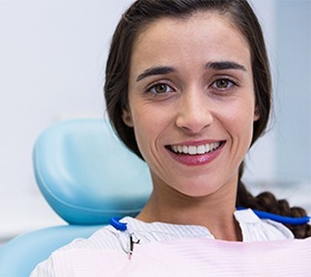 Woman smiling during her dental appointment while looking at camera.