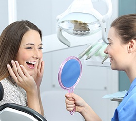 Excited woman admiring her new porcelain veneers in Bloomfield Hills