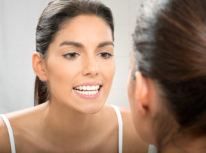 woman looking at white teeth in mirror