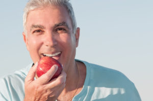 older man smiling holding apple