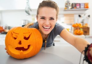Smiling woman with a carved pumpkin 
