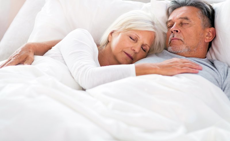 Man with sleep apnea soundly sleeping with wife in bed
