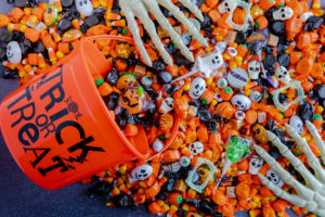 Orange pail spilling Halloween candy on black stone surface