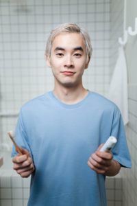 Man in bathroom holding toothbrush and toothpaste