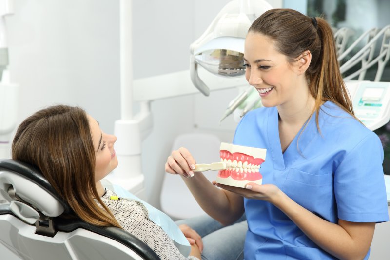 Dentist teaching patient how to brush to avoid gum disease