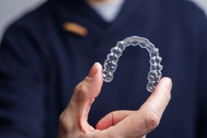 Dentist holding up clear aligner.